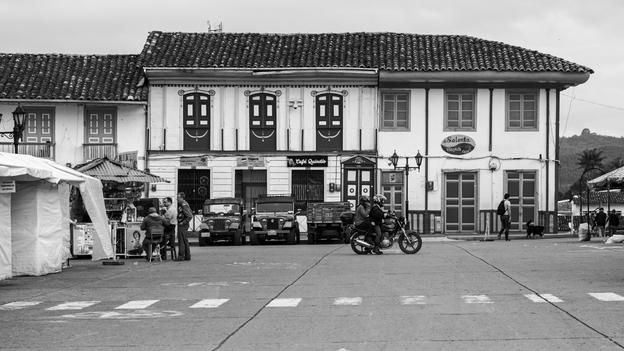Zwei Menschen auf einem Motorrad fahren über einen Platz in Salento in Kolumbien.