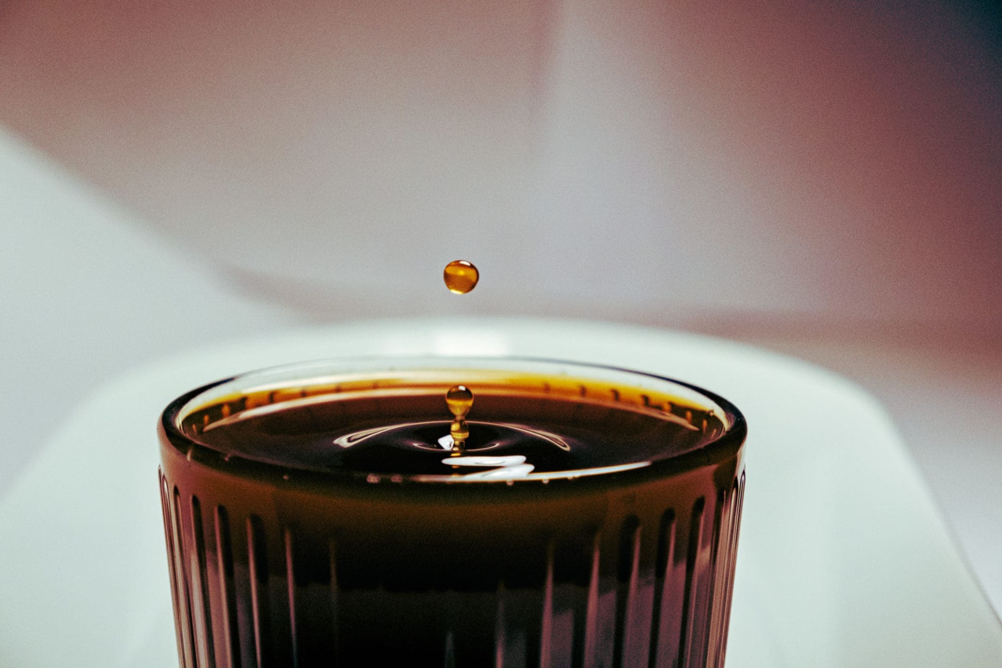 Ein einzelner Tropfen Kaffee fällt in ein Glas gefüllt mit Filterkaffee.