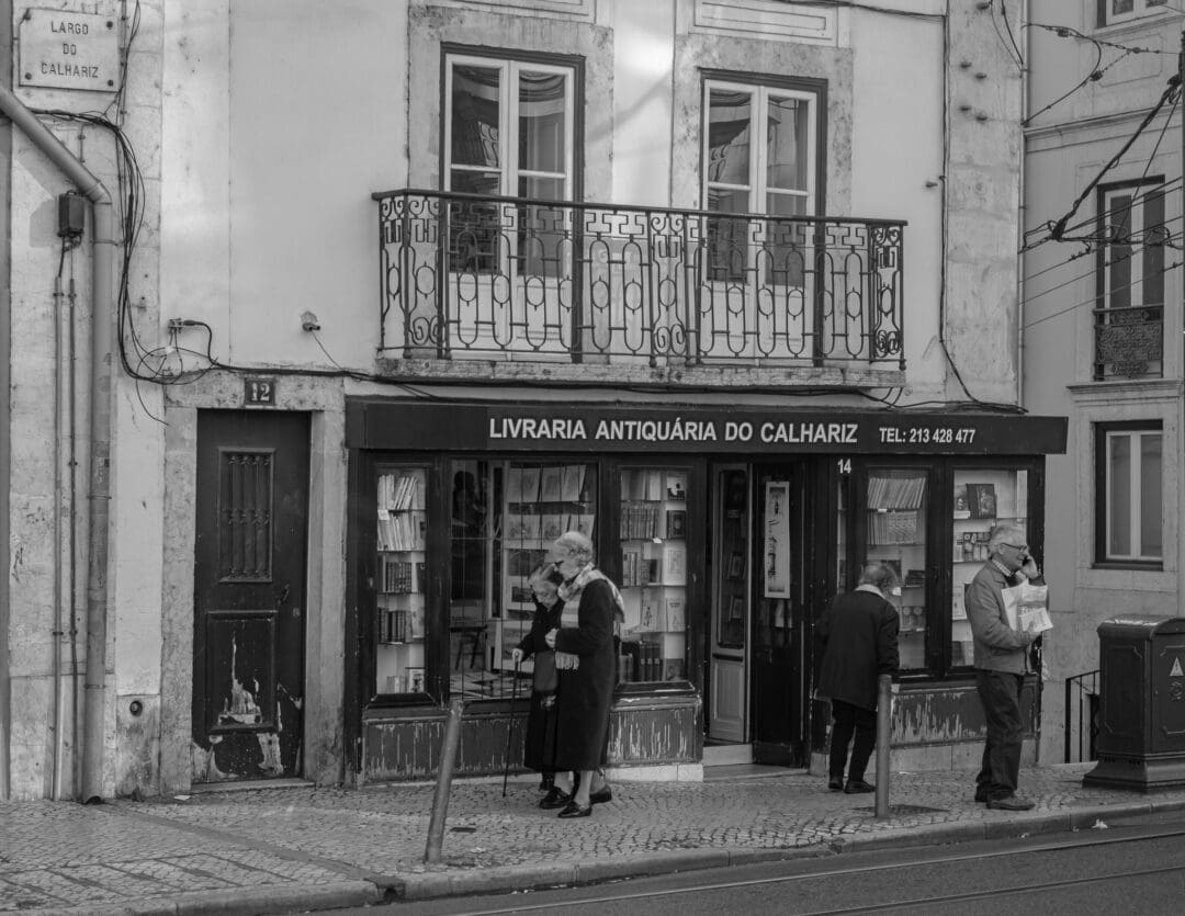 Eine Szene mit einigen älteren Menschen vor einer Antiquitäten-Buchhandlung in der Altstadt von Lissabon.