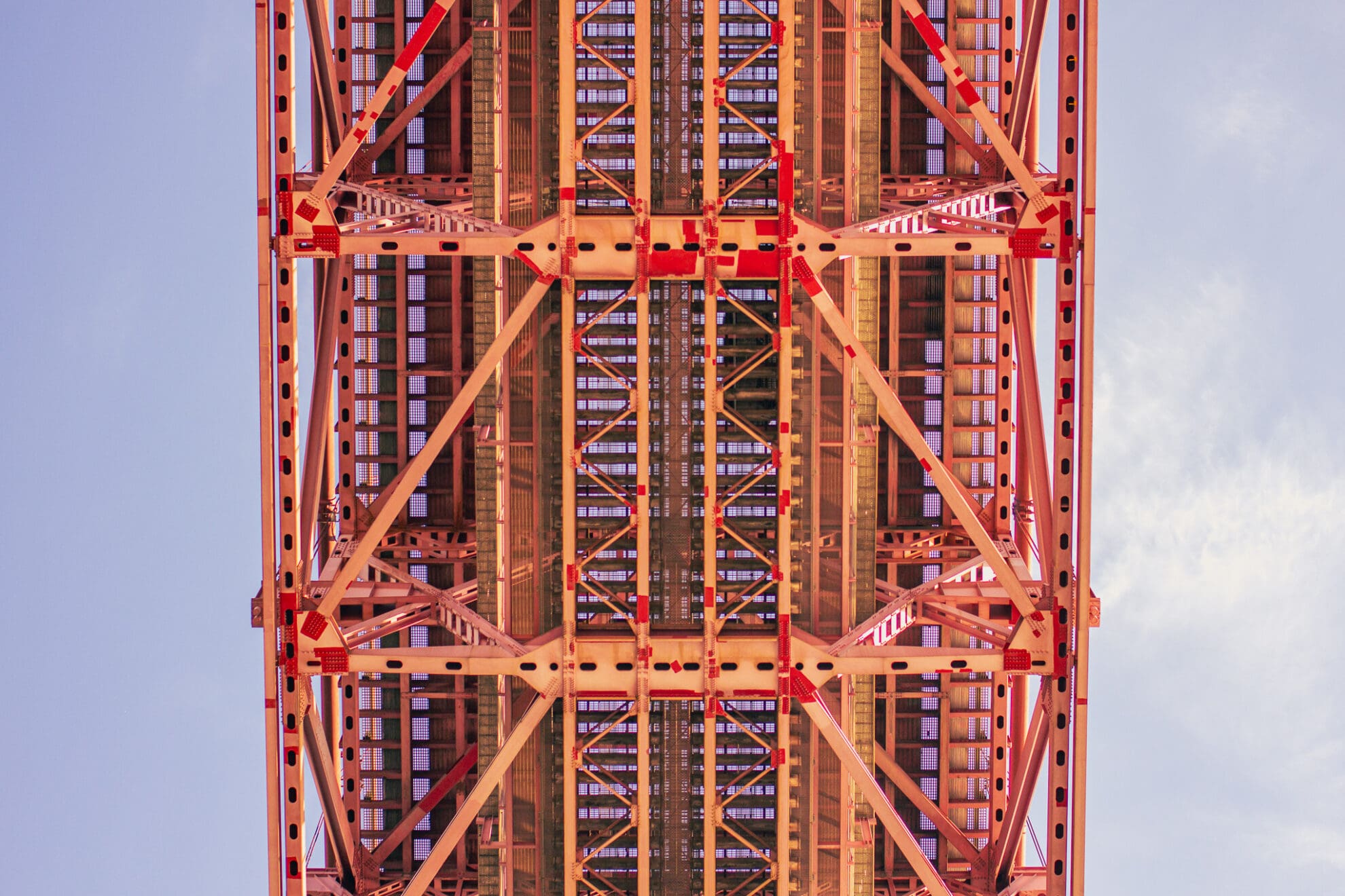 Rote Stahlkonstruktion einer Hängebrücke von unten fotografiert.